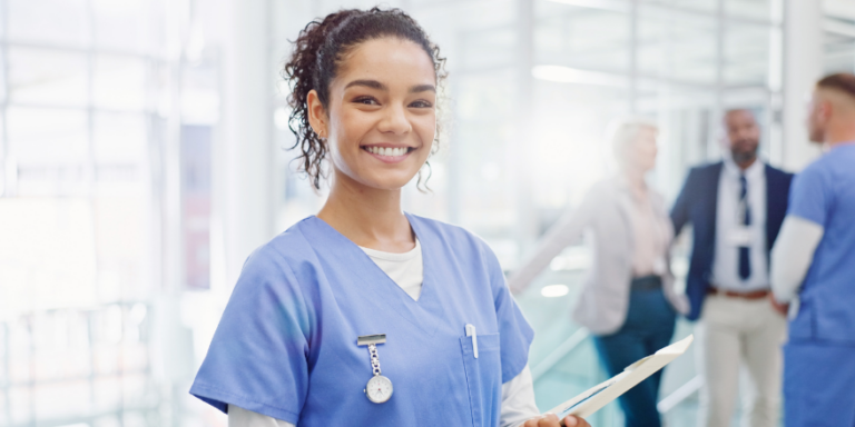 healthcare worker in smiling with clipboard in hospital setting